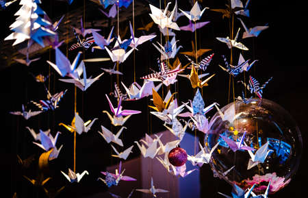Lots of origami swans hanging from the roof, seen from underneath in a softly illuminated roomの写真素材