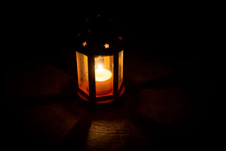 Spooky candle lamp with star shaped holes shining from inside. Lighting dimly the floor and projecting shadowsの写真素材