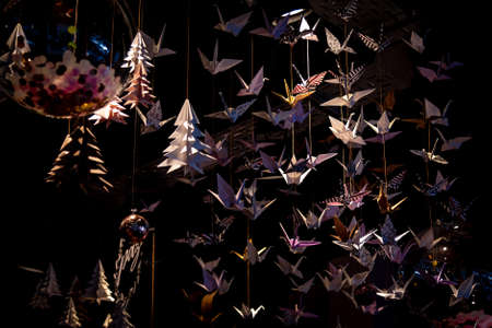 Lots of origami swans hanging from the roof, seen from underneath in a softly illuminated roomの写真素材