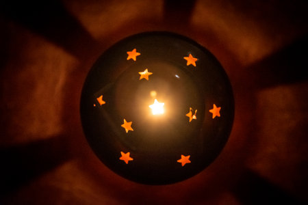 Candle lamp seen from above with star shaped holes shining from inside. Lighting dimly the floor and projecting shadowsの写真素材