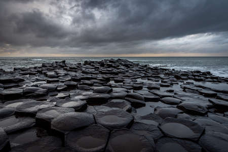 The natural hexagonal stones at the coast called Giants Causeway, a landmark in Northern Ireland with dramatic cloudy sky.の写真素材
