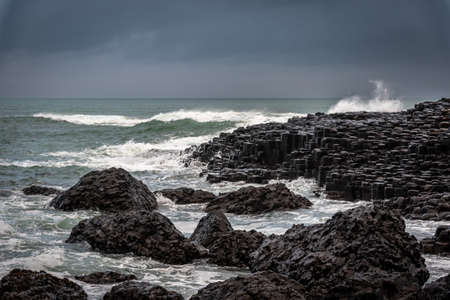 Sea waves hitting the natural hexagonal stones at the coast called Giants Causeway, a landmark in Northern Ireland.の写真素材