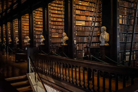 DUBLIN, IRELAND, DECEMBER 21, 2018: The Long Room in the Trinity College Library, home to The Book of Kells. Perspective view of the place, with large quantity of books and chest statues.のeditorial素材