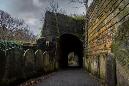 LIVERPOOL, ENGLAND, DECEMBER 27, 2018: Entrance to the creepy dark tunnel to the St Jamess Cemetery beside Liverpool Cathedral, with walls shaped by old moldy gravestonesのeditorial素材