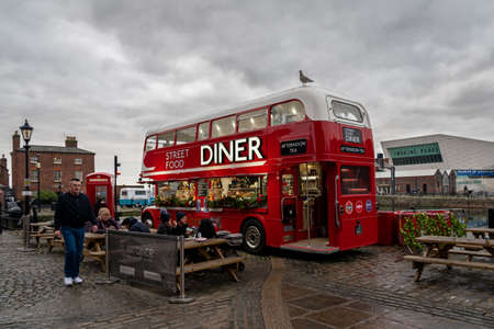 LIVERPOOL, ENGLAND, DECEMBER 27, 2018: People enjoying a meal on a cloudy day, beside a red double decker bus as food truck, decorated for christmas time.のeditorial素材