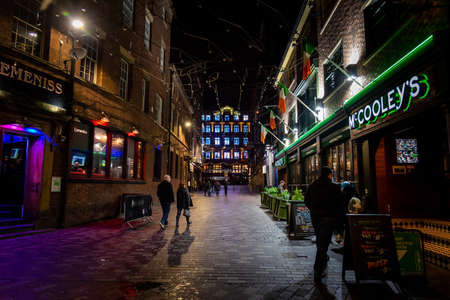 LIVERPOOL, ENGLAND, DECEMBER 27, 2018 People enjoying a pleasant night time in historic Matthew Street in Liverpool with a mixture of several colours of light from the bars and restaurants aroundのeditorial素材