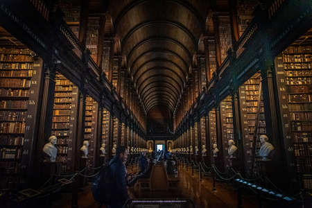 DUBLIN, IRELAND, DECEMBER 21, 2018: The Long Room in the Trinity College Library, home to The Book of Kells. Perspective view of the place, with large quantity of books and chest statues.のeditorial素材