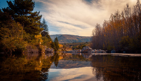 Mountain lake view with trees surrounding the calm water mirror at sunset in San Clemente in Cordoba, Argentinaの写真素材