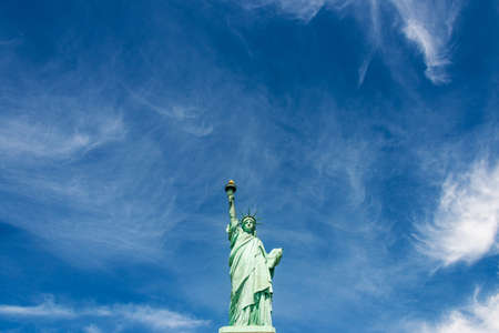 Wide-angle view of the Statue of Liberty against a cloudy blue sky, New York City.のeditorial素材