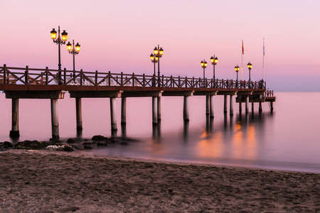 Illuminated wooden jetty on a beach in Marbella during sunset. Long exposure.の写真素材