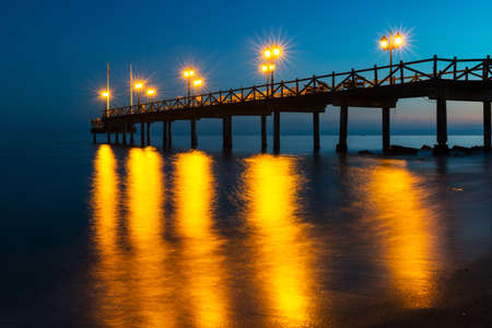 Illuminated wooden jetty on a beach in Marbella during sunset. Long exposure.の写真素材