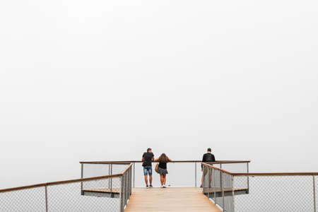 PONTEVEDRA, SPAIN - AUGUST 25, 2020: A small group of people wait for the fog to rise on a modern...