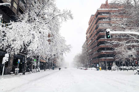 MADRID - JANUARY 9, 2021: Small groups of people walk in the snow along a commercial street in Madrid during the Filomena storm.のeditorial素材