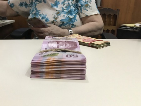 Business woman counting a stack of mexican peso money bills