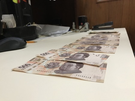 Some mexican peso money bills on a beige coloured table