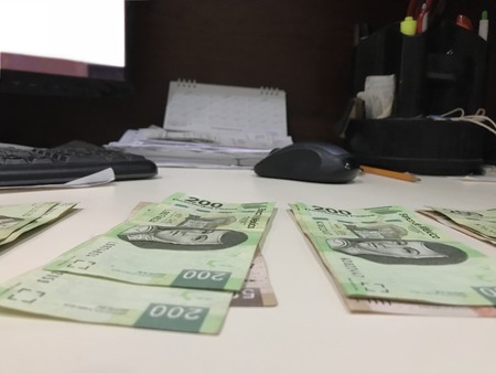Many mexican pesos bills distributed and spread on a beige colored deskの写真素材