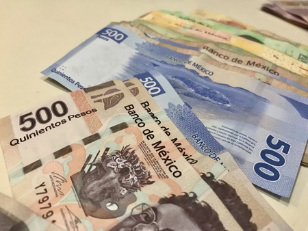 Many mexican pesos bills spread over a beige colored desk inside a small business officeの写真素材