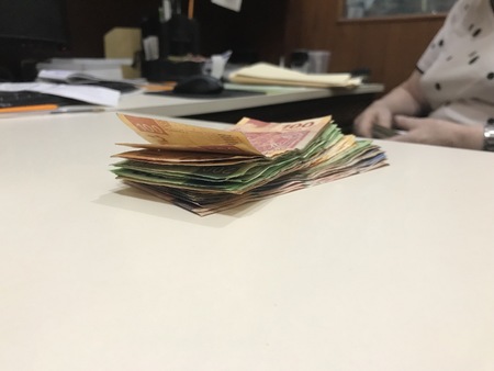 Many mexican pesos bills spread over a beige colored desk inside a small business office