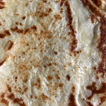 Texture view of a lightly burnt crepe with sugar poured over it