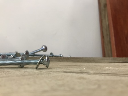 screws, nuts and rings on top of a wooden surface with white background wall
