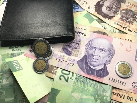 Many mexican pesos bills spread over a wooden desk inside a small business officeの写真素材
