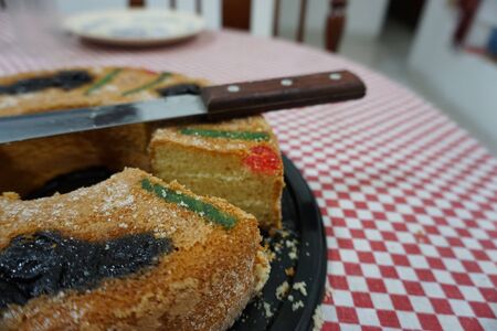 Top view of a Rosca de Reyes Epiphany Kings Cake on top of a red and white table cloth