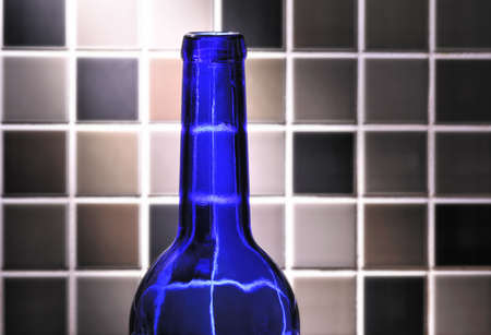 blue empty glass bottle with glazed tile backgroundの写真素材