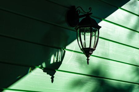 shadows and light - incandescent electric wall lamp on green wooden wall, lamp is offの写真素材