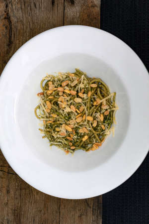 Ready-to-eat pasta with pesto sauce, soybeans and parmesan cheese in white plate on wooden backgroundの写真素材