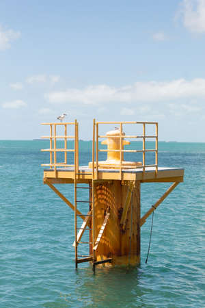 Yellow metal dolphin structure (ship mooring framework) in the sea with two small seagulls on topの写真素材