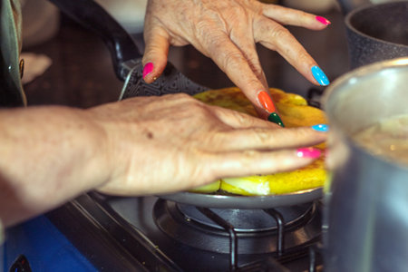 Hands of an unrecognizable woman with painted nails warming up yellow arepasの写真素材