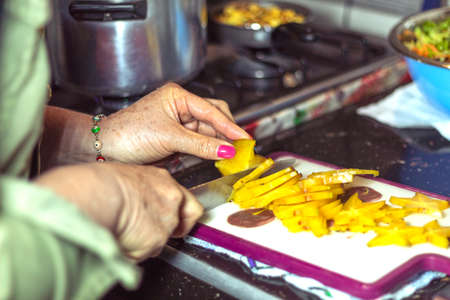 Unrecognizable person with colored nails cutting starfruit (tropical fruit) on a chopping board.の写真素材