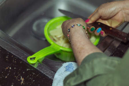 Unrecognizable woman with a knife in her hand after cutting potatoes