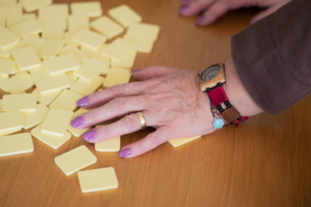 Hand of a senior woman mixing the tiles of a game of Rummyの写真素材