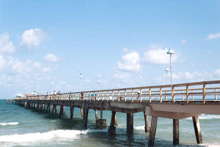 A pier on a calm sea with unrecognizable people fishingの写真素材