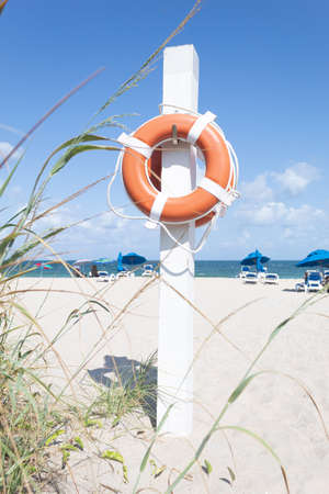 A pole with two lifesaver floats on a beach