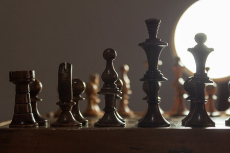 Chess pieces on a board with a strong light source in the backgroundの写真素材