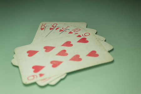 Poker cards K, Q, J, 10, 9 of hearts together on a green backgroundの写真素材