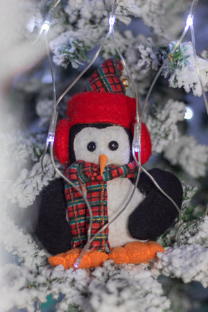 Christmas cute penguin doll on a snowy christmas treeの写真素材