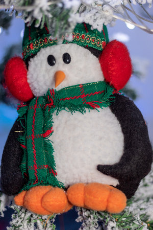 Christmas penguin doll on a snowy christmas treeの写真素材