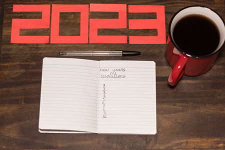 A small notebook on a desk to write 2023 new year resolutions on it. The notebook is next to a pen...