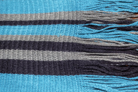 Close up of a hand knitted turquoise, gray and black scarf