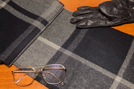 Different clothing accessories of a man on a wooden table, a checkered scarf with different shades...
