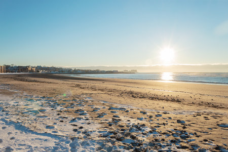 Cold sunrise on a beach with some snow on the sandの写真素材