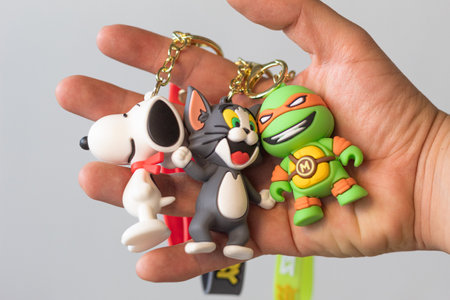 Bogota, Colombia - December 22, 2022: A man showing three cartoon shaped keychains. Snoopy, Tom from...