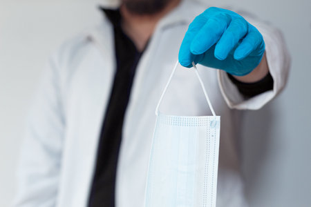 Doctor handing a face mask to cameraの写真素材