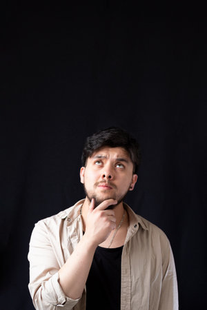 Light-eyed white young man touching his chin while looking up into an empty spaceの写真素材