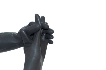 A hand in a black rubber glove interlocking fingers with another similar glove. Two interlocked hands isolated on a white background.の写真素材