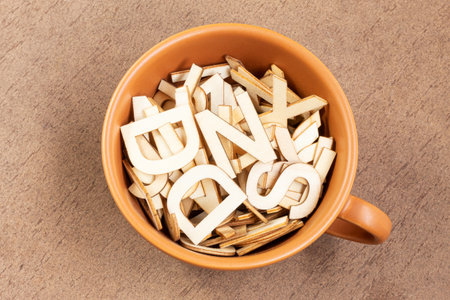 Top view of a small ceramic cup filled with wooden letters on a wooden backgroundの写真素材