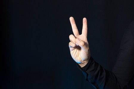 A business person showing two fingers up. Hand victory gesture isolated on a black background. Peace and love.の写真素材